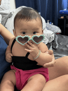 a baby wearing heart shaped sunglasses is being held by someone