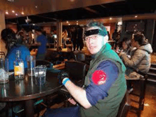 a man in a costume is sitting at a table in a bar .