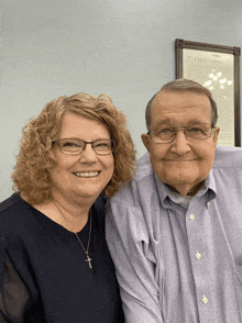 a man and a woman are posing for a picture in front of a framed document that says " chuck calvin "