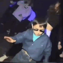 a man wearing sunglasses and a blue shirt is dancing in a club .