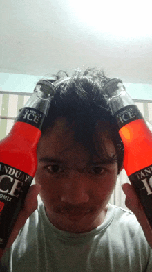 a man holding two bottles of tanduay ice