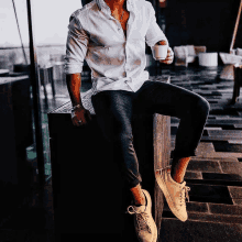 a man in a white shirt is sitting on a table with a cup of coffee in his hand