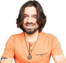 a man with long hair and a beard wears an orange shirt and a necklace