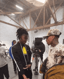 a group of people are standing in a room with a camera in the background