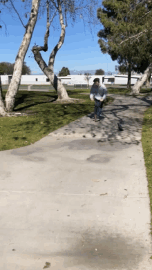 a person riding a skateboard down a concrete path in a park