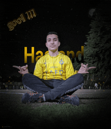 a young man in a yellow shirt sits in a lotus position in front of the word hazand