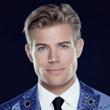 a man with blue eyes is wearing a white shirt and a blue jacket