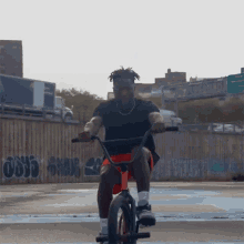 a man is riding a bike in front of a fence with graffiti on it including one that says 666