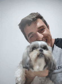 a man holding a small dog wearing a shirt that says " condicionado "