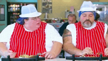 two men are sitting at a table eating a meal .