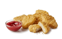 a bowl of ketchup sits next to chicken nuggets