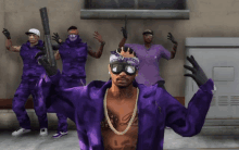 a man wearing a bandana and goggles stands in front of a group of men in purple