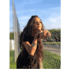 a woman leaning against a chain link fence with her hands on it