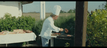 a man in a chef 's hat prepares food on a grill outside