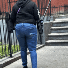 a woman wearing jeans and a black hoodie with the word new york on the arm