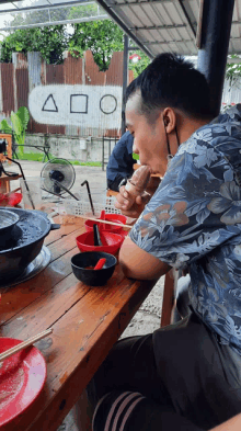 a man sitting at a table with a bowl of food and a sign that says aoo on it