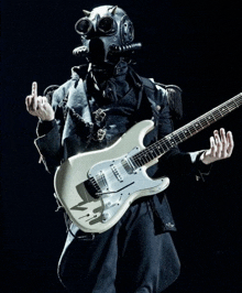 a man wearing a gas mask is playing a guitar