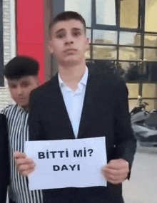 a man in a suit holding a sign that says bitti mi dayi