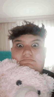 a young man holds a stuffed animal in front of his face