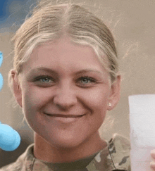 a woman in a military uniform is smiling while holding a piece of paper in her hand .