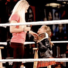 a woman in a pink shirt is talking to a little girl in a wrestling ring with the word w on it