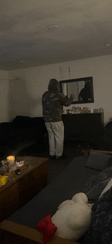 a man in a camo hoodie is standing in a living room