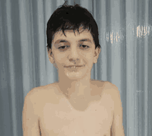 a young boy without a shirt is standing in front of a shower curtain