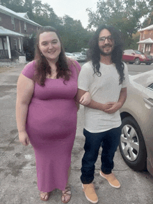 a woman in a purple dress stands next to a man with long hair and glasses