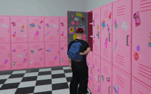 a person in a locker room with pink lockers and stickers on them