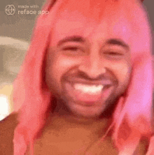 a man with pink hair is smiling for the camera .