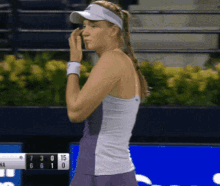 a woman wearing a visor is standing in front of a scoreboard that shows the score of 7 to 15