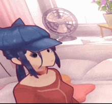 a cartoon girl wearing a blue hat is sitting on a bed in front of a fan