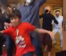 a group of people are dancing in a room while wearing masks .