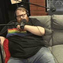 a man is sitting on a couch talking into a microphone .