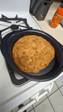 a bottle of reese 's peanut butter sits on a stove next to a cookie in a pan