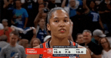 a female basketball player stands in front of a crowd while wearing a jersey that says thomas .