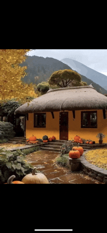 a yellow house with a thatched roof is decorated with pumpkins