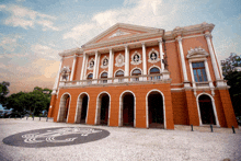 a large building with arches and columns has a g on the ground in front