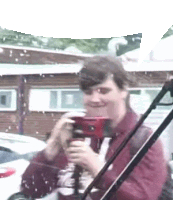 a man is taking a picture with a camera while standing in front of a car .