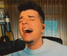 a man is singing into a microphone while wearing ear buds .