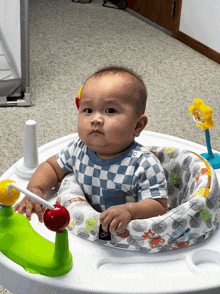 a baby is sitting in a baby walker with a toy on top of it