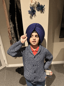 a young boy wearing a blue turban and a sweater