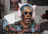 a man wearing a cat ear headset and sunglasses is making a funny face