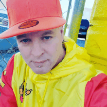 a man wearing an orange hat and a yellow jacket has a piercing on his nose