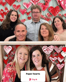 a group of people standing in front of a wall with paper hearts