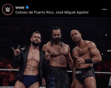 three wrestlers are posing for a picture in a wrestling ring