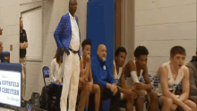 a group of basketball players are sitting on a bench in front of a sign that says " chesterfield christian "