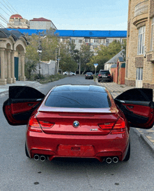 a red bmw with its doors open is parked on the side of the road