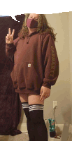 a woman wearing a carhartt sweatshirt and knee high socks giving a peace sign