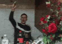 a man holding a bottle of coca cola in front of flowers